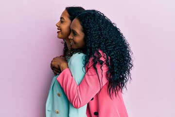 African american mother and daughter wearing business style looking to side, relax profile pose with natural face and confident smile.