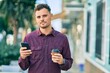 © Krakenimages.com - Young hispanic man with serious expression using smartphone and drinking coffee at the city.