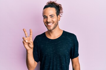 Poster - Young handsome man with long hair wearing casual clothes smiling with happy face winking at the camera doing victory sign. number two.