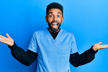 Poster - Handsome hispanic man with beard wearing blue male nurse uniform celebrating victory with happy smile and winner expression with raised hands