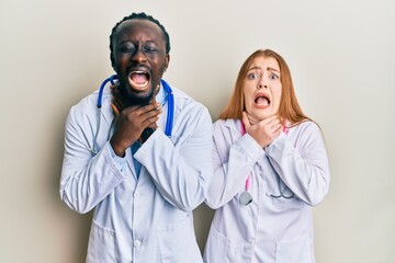 Sticker - Young interracial couple wearing doctor uniform and stethoscope shouting and suffocate because painful strangle. health problem. asphyxiate and suicide concept.