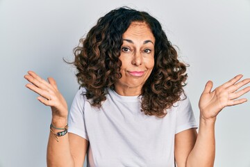 Poster - Middle age hispanic woman wearing casual white t shirt clueless and confused with open arms, no idea and doubtful face.