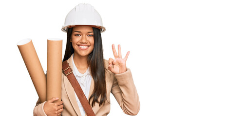 Sticker - Beautiful hispanic woman holding paper blueprints doing ok sign with fingers, smiling friendly gesturing excellent symbol