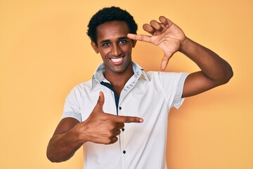 Canvas Print - African handsome man wearing casual shirt smiling making frame with hands and fingers with happy face. creativity and photography concept.