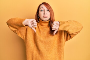 Poster - Beautiful redhead woman doing negative thumbs down gesture depressed and worry for distress, crying angry and afraid. sad expression.