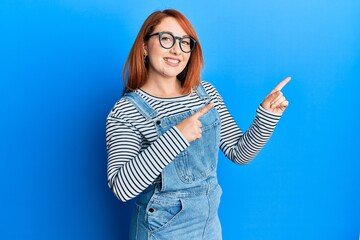 Poster - Beautiful redhead woman wearing casual clothes and glasses smiling and looking at the camera pointing with two hands and fingers to the side.