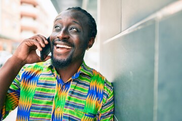 Poster - Young african american man talking on the smartphone leaning on the wall at street of city.