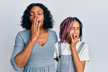 Wall Mural - Beautiful african american mother and daughter wearing casual clothes and hugging bored yawning tired covering mouth with hand. restless and sleepiness.