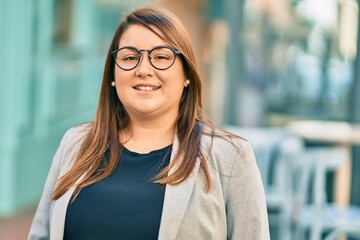 Young hispanic plus size businesswoman smiling happy standing at the city.