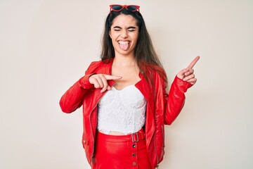 Wall Mural - Brunette teenager girl wearing red leather jacket sticking tongue out happy with funny expression.