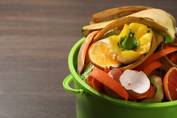 Wall Mural - Natural garbage in trash bin on wooden background, closeup with space for text. Composting of organic waste