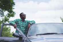 African Man Wearing Sunglasses And Smiling With A Car
