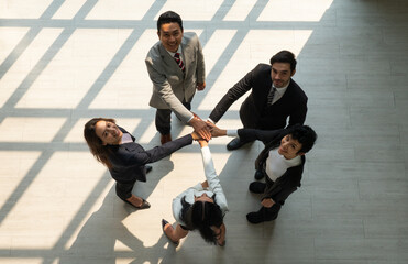 view from above of multiethnic business team touching hands together as a sign of unity in internation corporate office. diversity in business concept