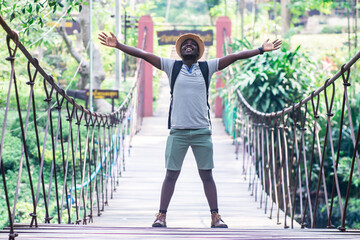 Wall Mural - African man traveler standing on the bridge with smile and happy