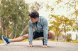 © Charnchai saeheng - young man stretching in the park before running. Young man workout before fitness training at the park. Healthy and exercise young man warming up on the road beside the forest.