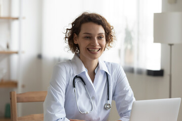 Wall Mural - Smiling young Caucasian female doctor in white medical uniform consult patient or client in hospital. Happy woman GP or therapist talk with customer at consultation. Medicine, healthcare concept.