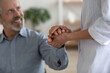 © fizkes - Close up of supportive female doctor in white medical uniform comfort caress hold senior male patient hand. Caring woman nurse or caregiver support optimistic mature man. Elderly healthcare concept.