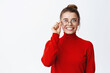 © Cookie Studio - Smiling successful businesswoman with hairbun, touching her glasses and looking pleased at empty space, staring left at logo banner, white background