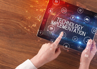 Close-up of a tablet with TECHNOLOGY IMPLEMENTATION inscription, innovative technology concept