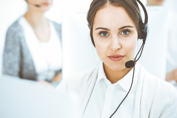 Wall Mural - Call center. Group of diverse operators at work. Beautiful woman in headset communicating with customers of telemarketing service. Business concept