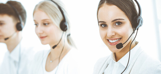 Wall Mural - Call center. Group of diverse operators at work. Beautiful woman in headset communicating with customers of telemarketing service. Business concept