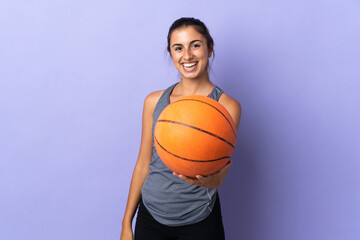 Young hispanic woman over isolated purple background playing basketball