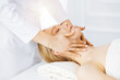 © Iryna - Beautiful caucasian woman enjoying facial massage with closed eyes in sunny spa salon. Relaxing treatment in medicine