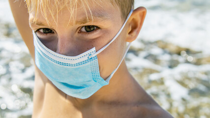 8 years old cute boy wearing medical mask on the beach