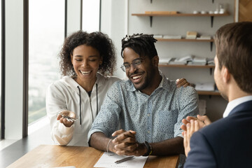 Close up overjoyed African American family received keys from realtor at meeting, excited satisfied clients purchasing new apartment, house, happy tenants excited by relocation, mortgage concept