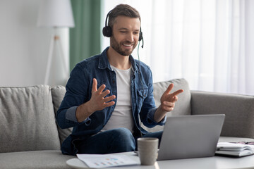 Wall Mural - Cheerful bearded man having video conference with colleagues from home