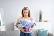 © Prostock-studio - Unhappy millennial housewife holding clothes for washing or ironing, unwilling to do domestic duties, indoors