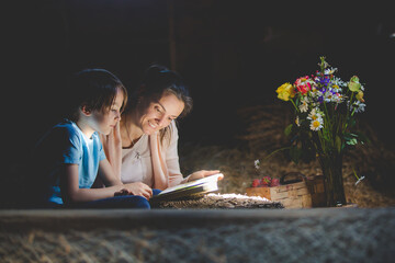 Poster - Beautiful mom and toddler blond boy, reading a book in the attic, nice atmosphere, flowers and strawberries