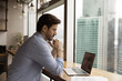 © fizkes - Close up thoughtful businessman wearing glasses looking at laptop screen, accountant working with financial project statistics, analyzing graphs and diagrams in modern office with panoramic window