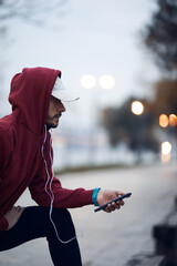 Wall Mural - Athletic sporty man training in hoodie sweatshirt in urban city park.