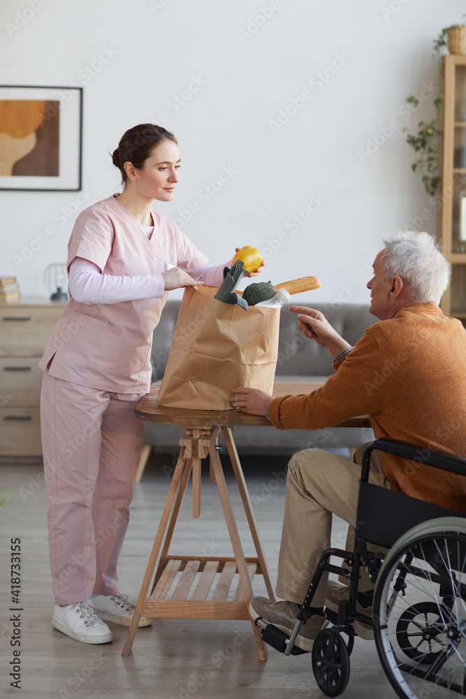 Vertical full length portrait of young female caregiver bringing ...