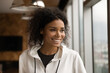 © fizkes - Head shot smiling dreamy African American young woman looking to aside, standing at home near window, thinking, visualizing good future, dreaming about new opportunities, planning, enjoying view
