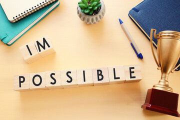 Poster - wooden cubes with the text impossible, removing the word im so it written possible. success and challenge concept.