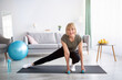 Athletic senior lady doing stretching exercises with dumbbells during her home workout, free space