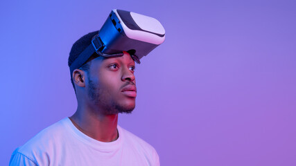 Wall Mural - Handsome Black Man Wearing VR Glasses Looking Aside Over Purple Background