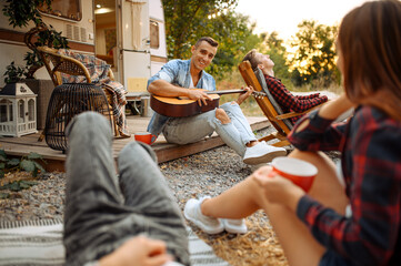 Wall Mural - cheerful friends sing songs on picnic at camping