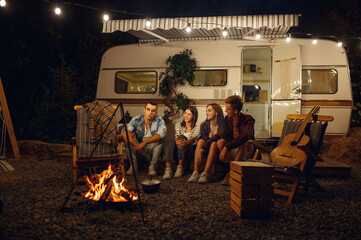 Wall Mural - friends sitting by campfire in the night, camping
