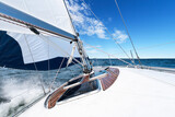 Fototapeta  - White sailing boat and bright blue sea and sky with water spraying