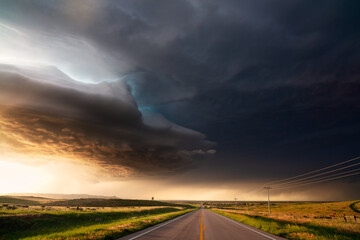 Wall Mural - Supercell storm with dramatic clouds over a road at sunset