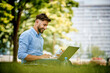 © baranq - Portrait of young businessman sitting with sandwich and laptop in the park