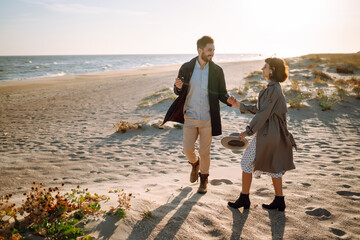 Stylish couple walking and hugging by the sea. Lovely hipster couple enjoying time together. The concept of youth, love and lifestyle. Springtime.