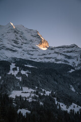 Wall Mural - village in the alps of switzerland after sunset in the winter with mountains and snow