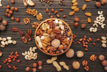 Wall Mural - Assortment of nuts in bowls. Cashews, hazelnuts, walnuts, pistachios, pecans, pine nuts, peanuts, macadamia, almonds, brazil nuts. Food mix on wooden background, top view, copy space