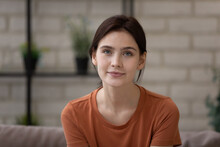 Headshot Portrait Of Confident Millennial Woman Sit On Sofa At Living Room Looking At Camera Webcam Take Part In Virtual Event Conference. Young Female Student Having Online Job Interview By Videocall