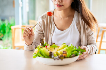 Young woman eating a healthy salad mixes with vegetable and fruit at the restaurant, Healthy lifestyle and diet concept