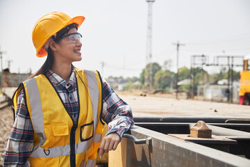 Female contractor in yellow protective clothing is standing outdoors.